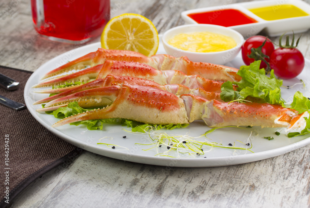 Boiled crab claws with sauce , lemon and cherry tomatoe with tasty drink over wooden background Boiled crab claws with sauce , lemon and cherry tomatoe with tasty drink over wooden background