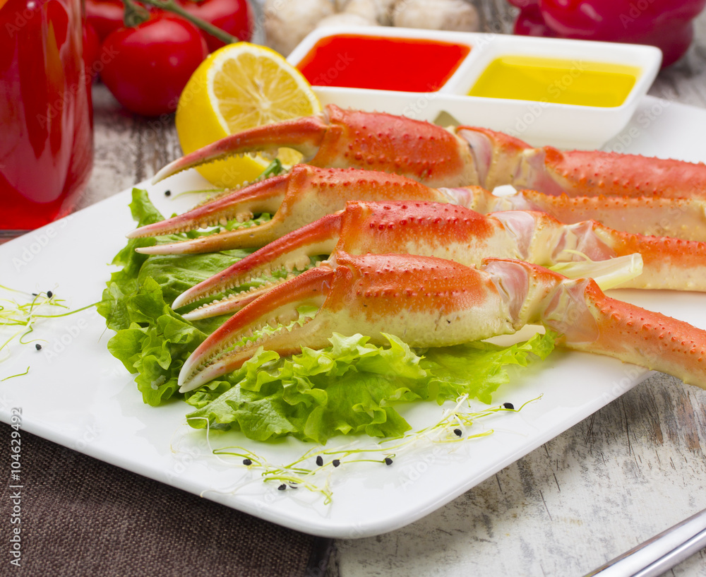 Boiled crab claws with sauce , lemon and cherry tomatoe with tasty drink over wooden background Boiled crab claws with sauce , lemon and cherry tomatoe with tasty drink over wooden background