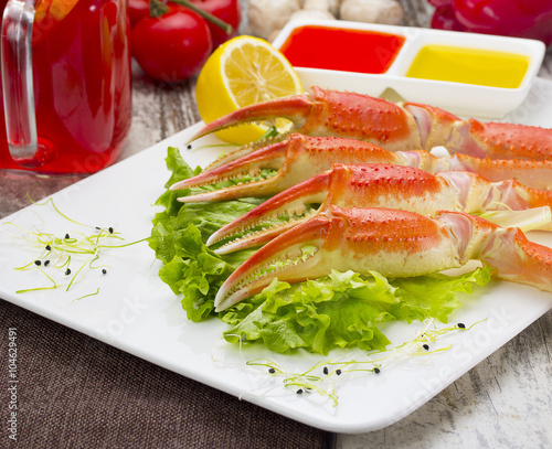 Boiled crab claws with sauce , lemon and cherry tomatoe with tasty drink over wooden background