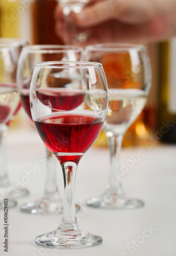 Glasses with different kind of wine and human hand holding wineglasses in the background