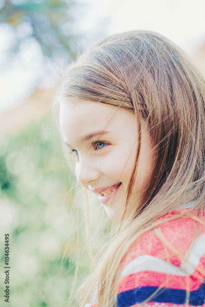 Naklejka premium Spring fairy. Portrait of beautiful little girl with brownish blond hair and blue eyes standing outdoor on natural background.