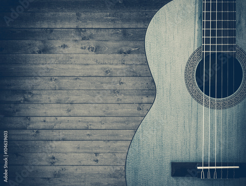 Part of a blue acoustic guitar on a gray wooden background.