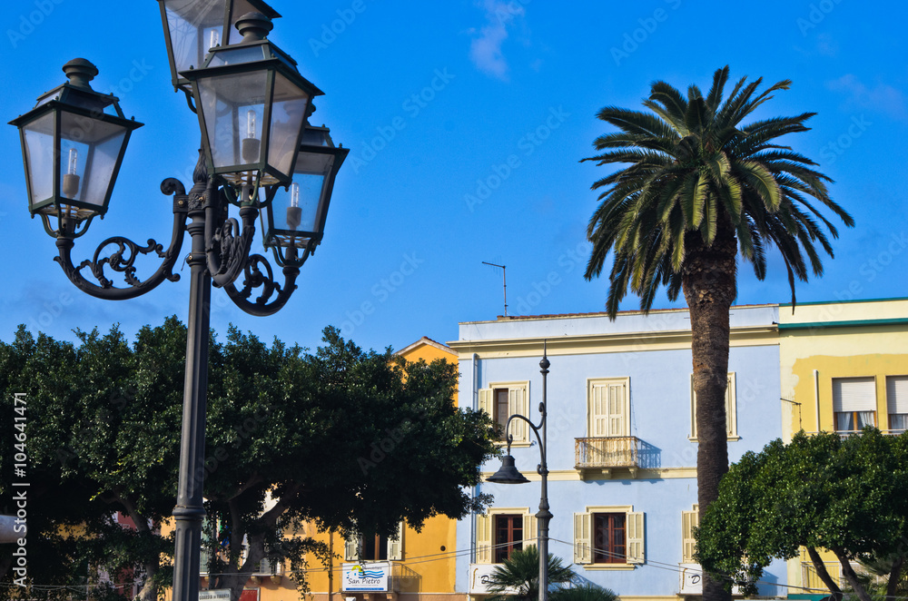 Lantern if front of colorful buildings at Carloforte harbor, San Pietro island, Sardinia, Italy