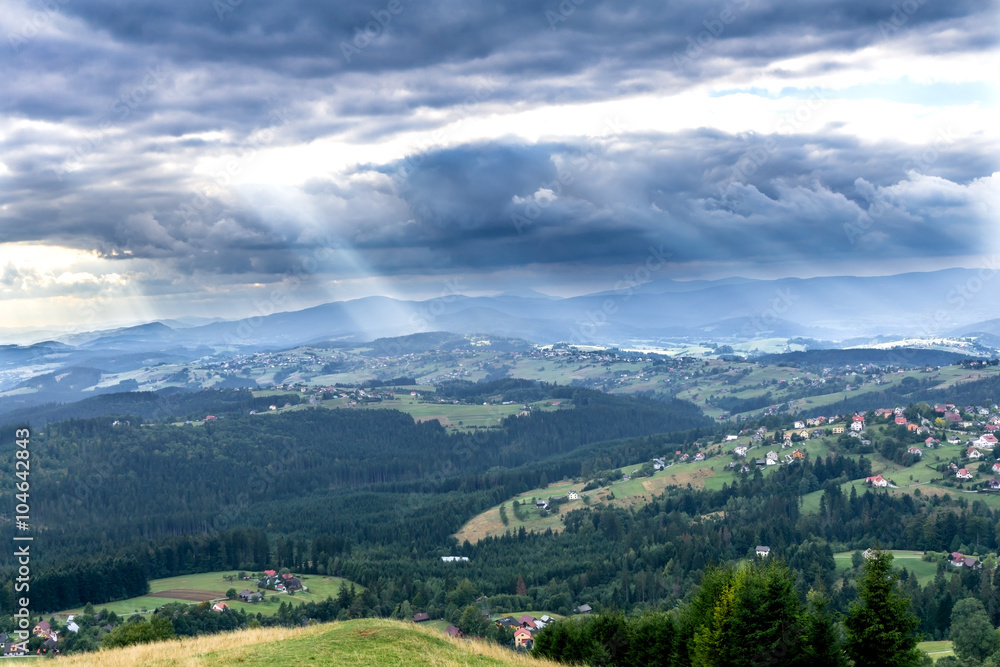 Sunbeams through clouds over Silesian Beskids mountains, Poland.