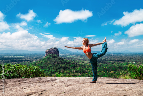 Young woman doing yoga pose on the mountain Pidurangala Rock, Sri Lanka. Sigiriya