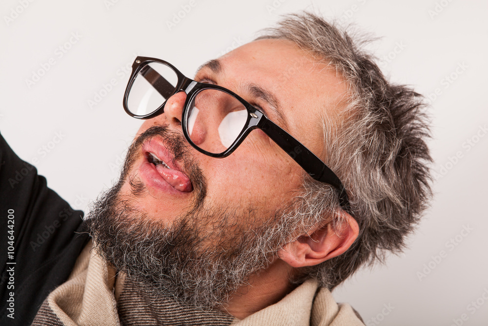 Obraz premium Crazy looking old man with grey beard nerd big glasses show tongue