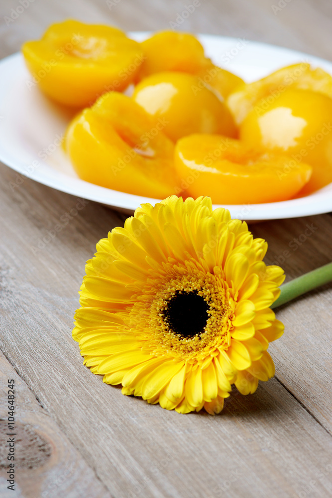 yellow gerber and halves of peaches in white dish yellow gerber and halves of peaches in white dish