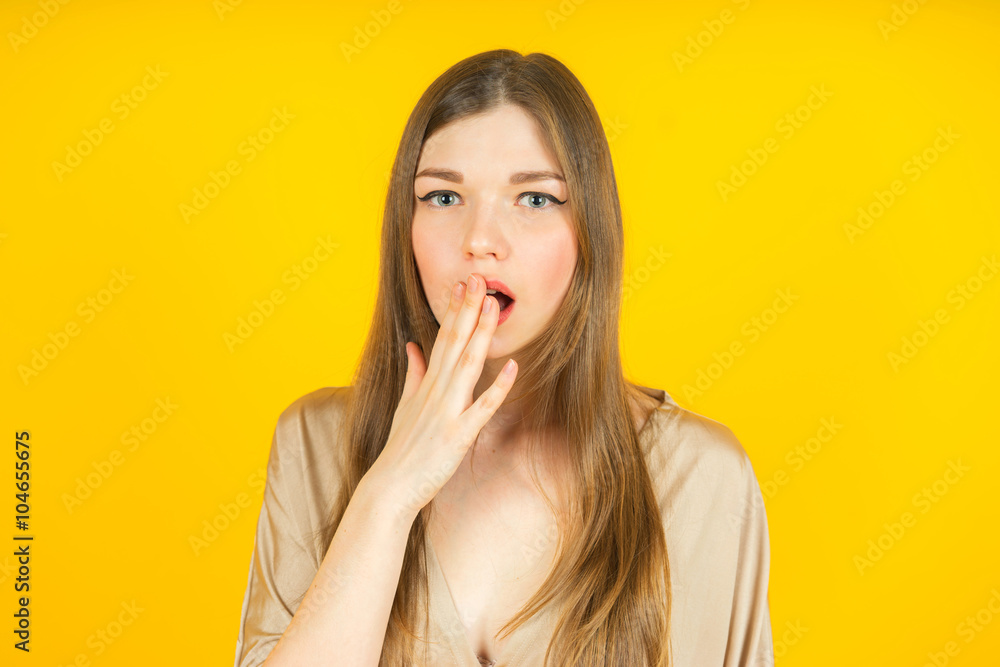 Portrait of surprised beautiful girl closing her mouth in amazement and open-mouthed. Over yellow background. Portrait of surprised beautiful girl closing her mouth in amazement and open-mouthed. Over yellow background.