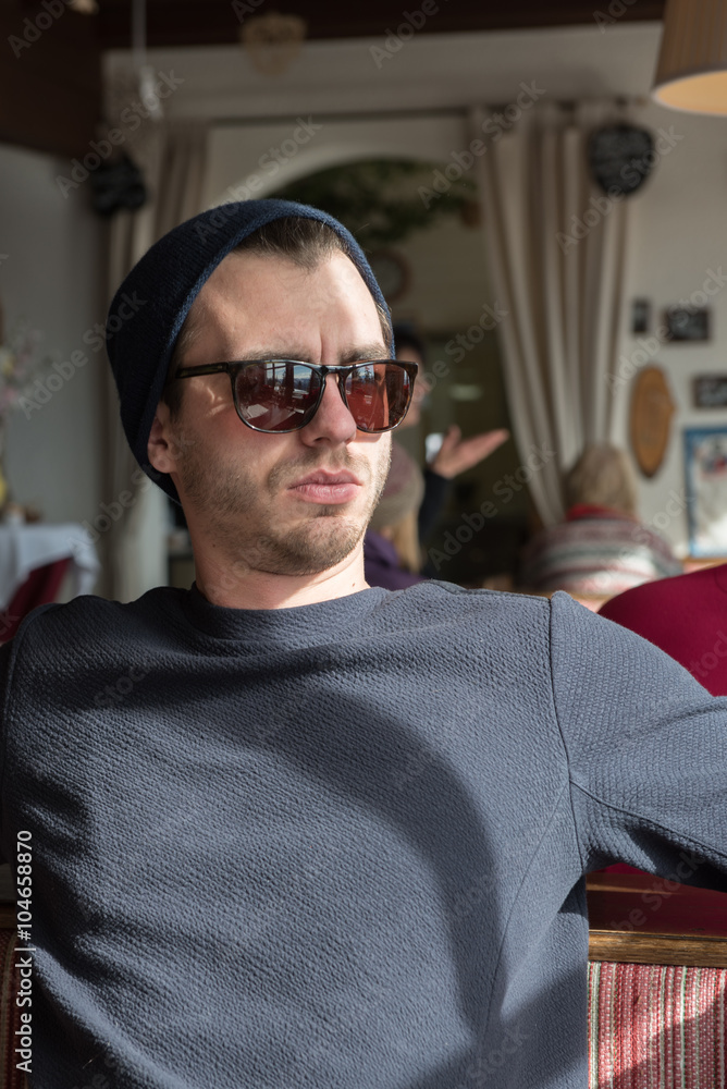 young handsome hipster with sunglasses looking out of the window young handsome hipster with sunglasses looking out of the window