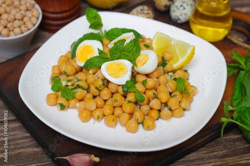 Mediterranean cuisine. Dish of chickpeas with mint, olive oil and lemon sauce on a wooden background
