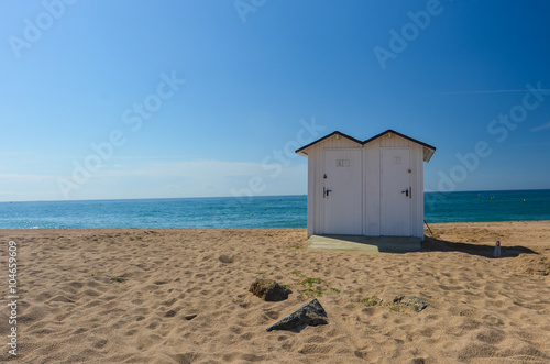 Small toilet booth on the beach with ocean
