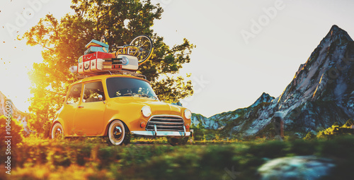 Obraz Śliczny mały samochód retro jedzie wspaniałą wiejską drogą o zachodzie słońca