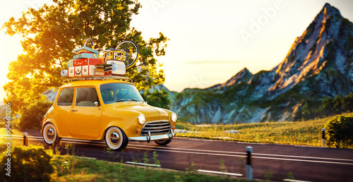 Cute little retro car goes by wonderful countryside road at sunset