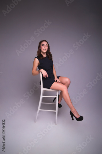 Young elegant woman in black dress, shoes. Sitting and posing i