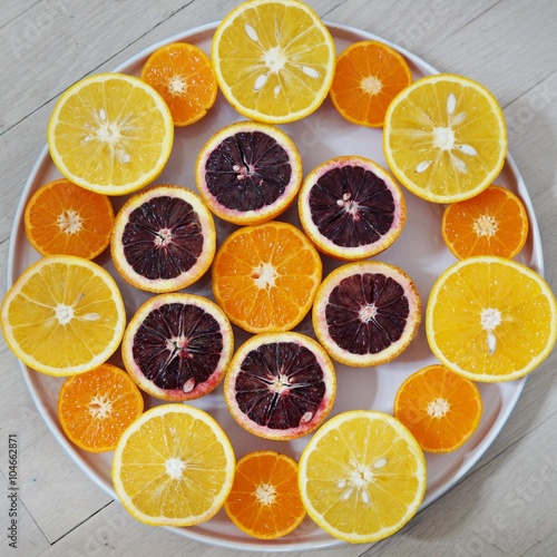  Ruby red blood oranges, navel oranges, and clementines cut in half on a white platter