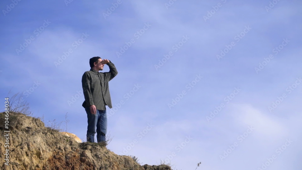 young man standing at the edge of the precipice and looking far young man standing at the edge of the precipice and looking far