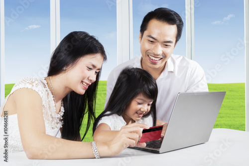 Young parents and their child buy online © Creativa Images