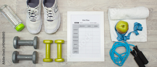 Various sport equipment with diet plan on wooden background