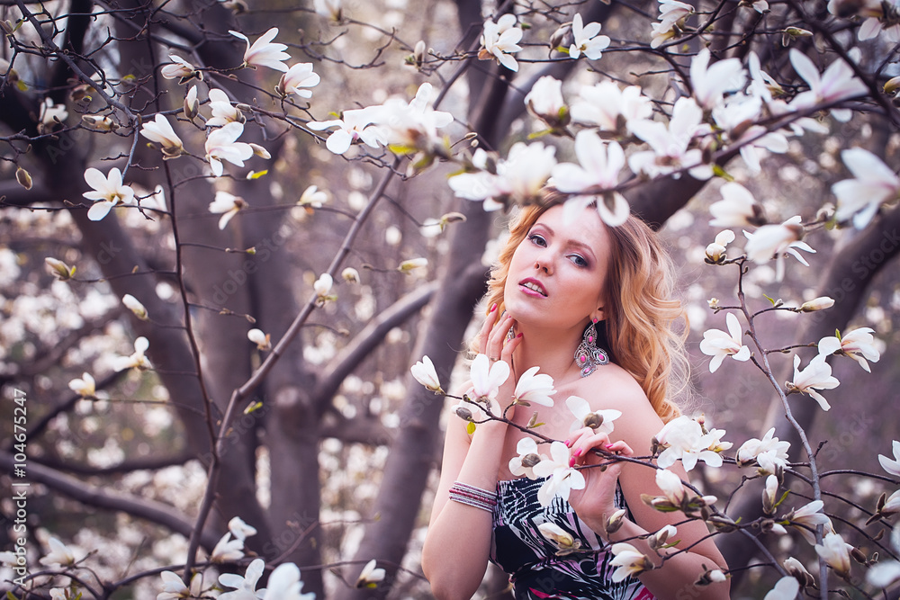 Fototapeta premium Beauty smiling woman near white magnolia