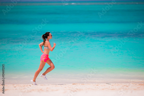 Fit young woman running along tropical beach in her sportswear  © travnikovstudio