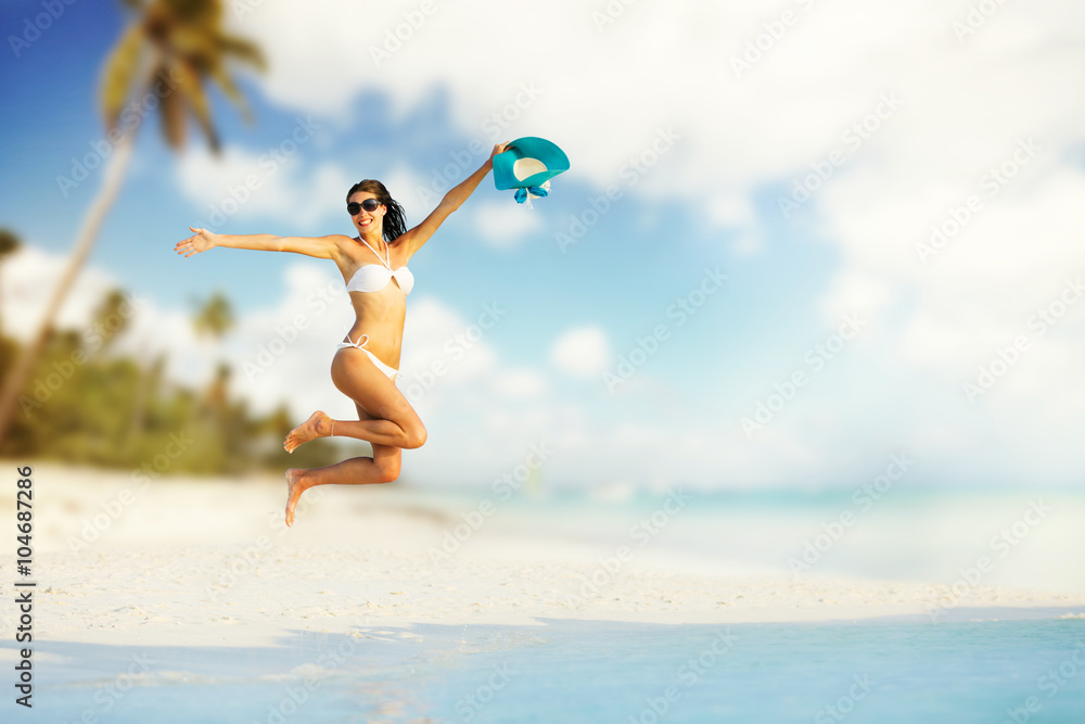 Beautiful girl jumping on tropical beach