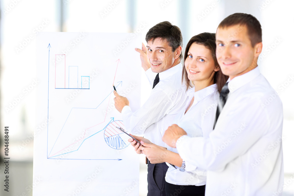 A senior business executive delivering a presentation to his colleagues during a meeting or in-house business training