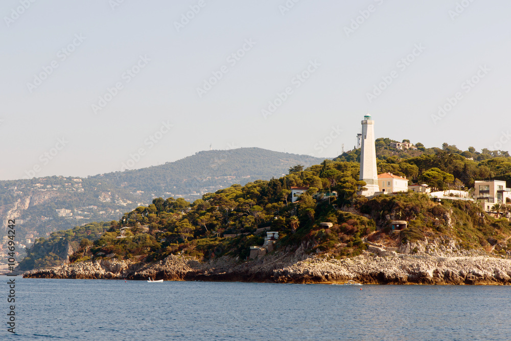 Color DSLR stock landscape image of lighthouse and homes along the Mediterranean coast of the French Riviera. Horizontal with copy space for text