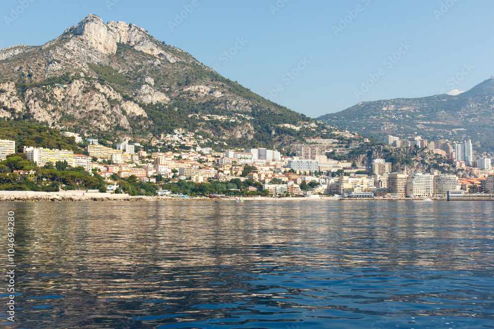 Color DSLR stock image of luxury houses along the French Riviera coastline with a mountain in the background and the blue Mediterranean Sea in the foreground.  Horizontal with copy space for text