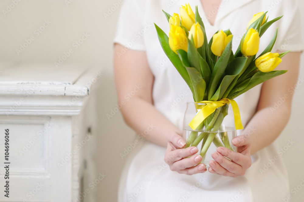 Yellow, fresh tulips in the hands of a beautiful woman.