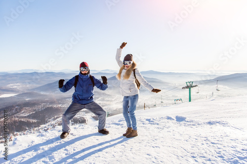 Girl and guy in masks for snowboarding rejoice amid the ski slopes