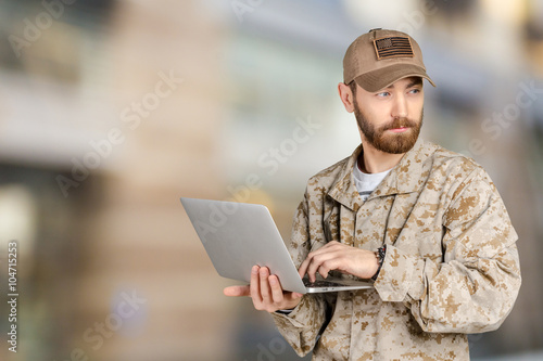 Portrait of young army soldier with a laptop
