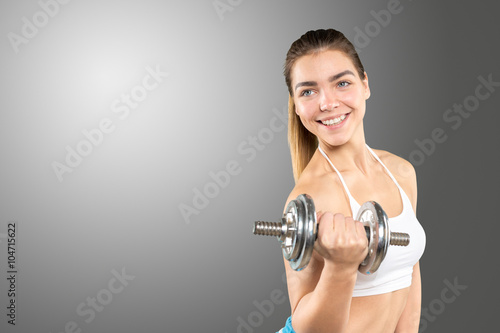 sporty muscular female wearing sports clothes working out with dumbbell