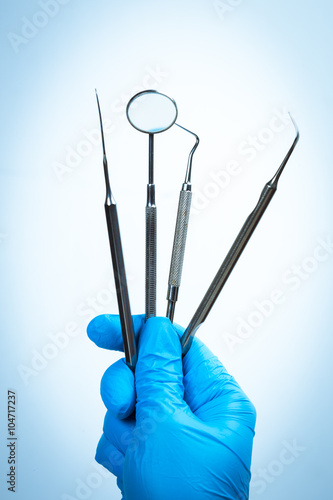 Gloved hand holding dental instrument