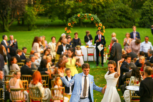 Valokuvatapetti rich stylish groom and bride raise up hand background guests at