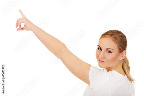 Young woman pointing on copy space or something