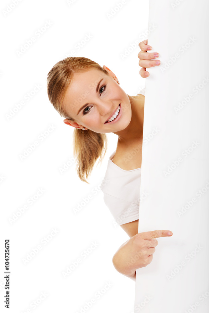 Smiling young woman pointing for empty banner