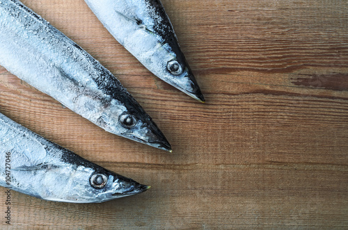 Frozen fish Pacific Saury on a wooden board photo