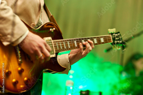 Musician plays on guitar in grey jacket