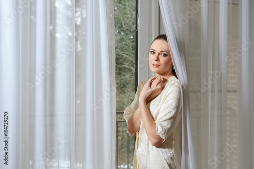 Free Download pretty young lady in silk peignoir near window behind the curtai - GFXLoad