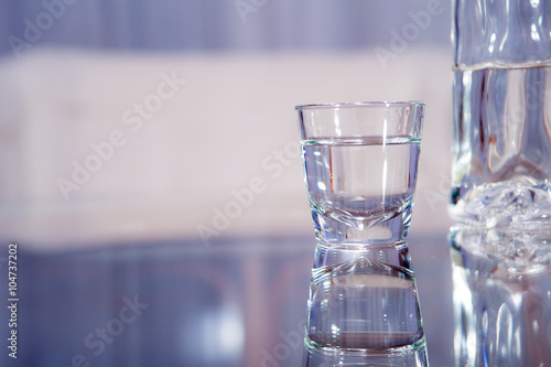 vodka glass / A vodka glass with a bottle standing on the glass table
