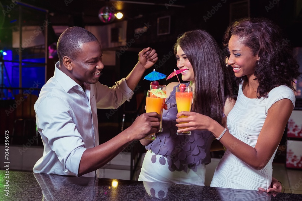 Young friends enjoying while having cocktail drinks at bar