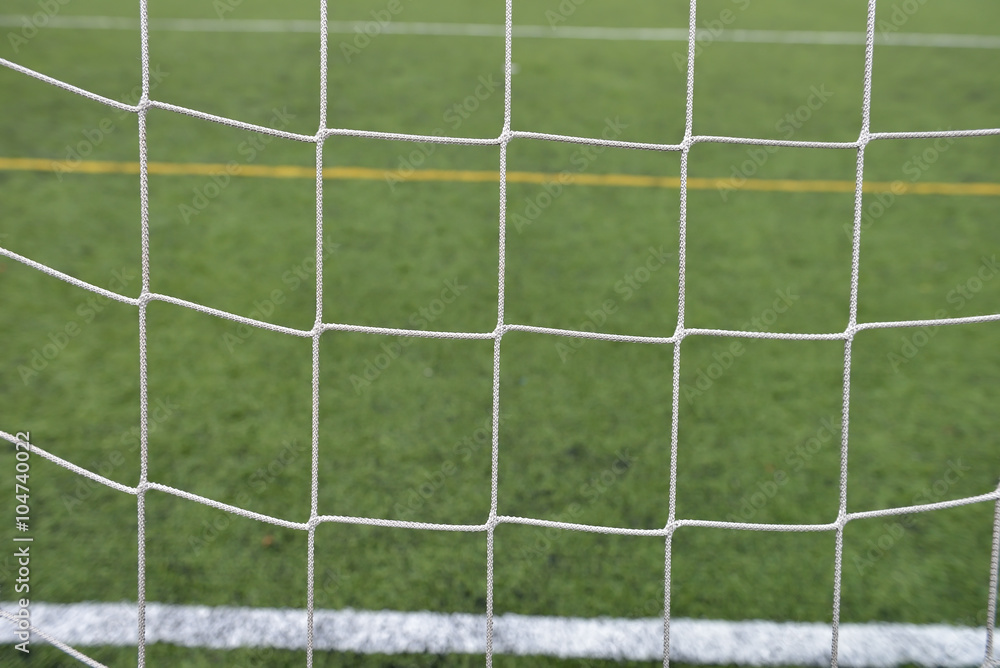 Close up detail of a soccer net against green grass on a cloudy