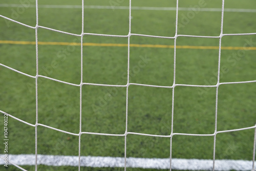 Close up detail of a soccer net against green grass on a cloudy