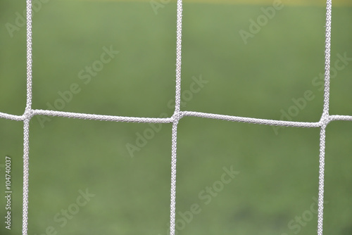 Close up detail of a soccer net against green grass on a cloudy photo