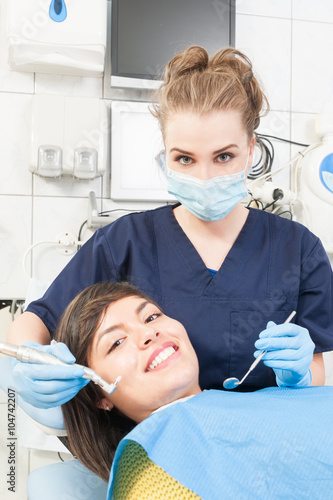 Smiling patient and dentist wearing uniform and mask