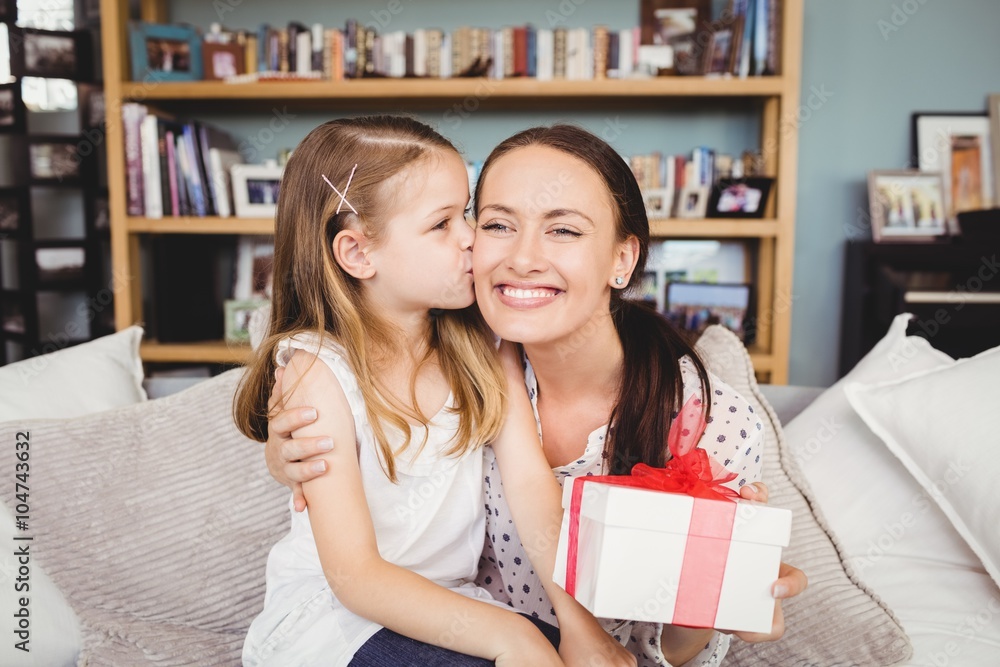 Daughter kissing mother with gift box