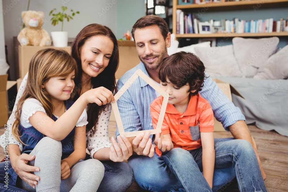 Smiling family holding house shape at home Smiling family holding house shape at home