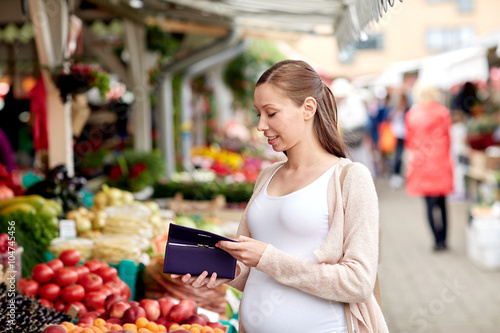 pregnant woman with wallet buying food at market