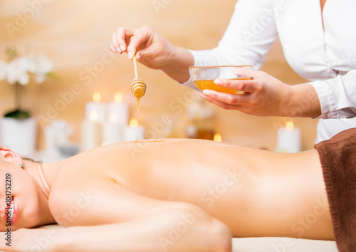 Woman enjoying spa treatment with honey