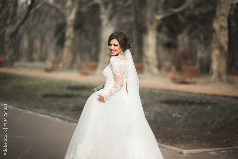 Beautiful bride in the park on her wedding day with bouquet